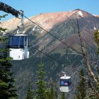 Scenic gondola ride over lush forest and snow-capped mountains