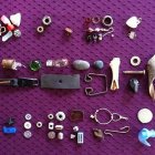 Colorful eclectic objects on purple background: telescope, tassels, gears, baubles