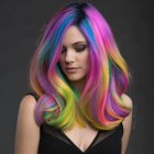 Rainbow-colored wavy hair and blue eyes on dark background