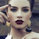 Surreal portrait of woman with blue makeup and spider on shoulder