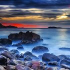 Misty seascape at dusk with rocky cliffs, tranquil sea, twilight sky, stars, and cres