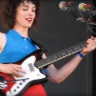 Blue-haired woman playing electric guitar surrounded by colorful bubbles