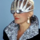 Avant-garde hat and collar with metallic textures on a gray backdrop