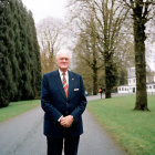 Military man in formal uniform with medals standing on tree-lined path