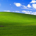 Lush green hill painting under blue sky with clouds and trees