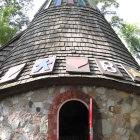 Stone tower with arched door and green vines, surrounded by ethereal trees under soft light