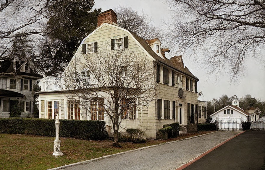 Vintage two-story home with sloped roof, stone and siding mix, chimneys, picket fence