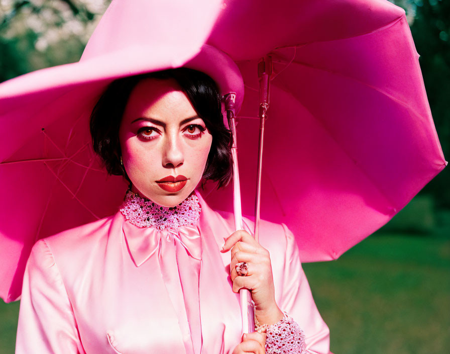 Dark-Haired Woman in Pink Outfit with Pink Umbrella in Green Setting