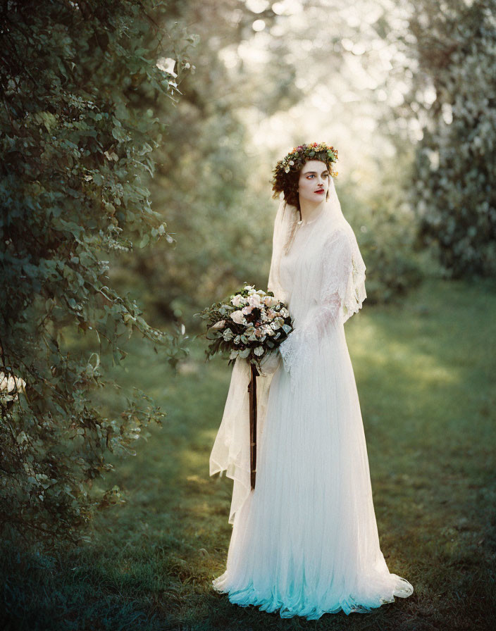 Bride in white gown with floral crown holding bouquet in serene grove