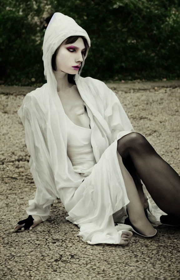 Person in White Hooded Robe with Dramatic Makeup on Gravel Path