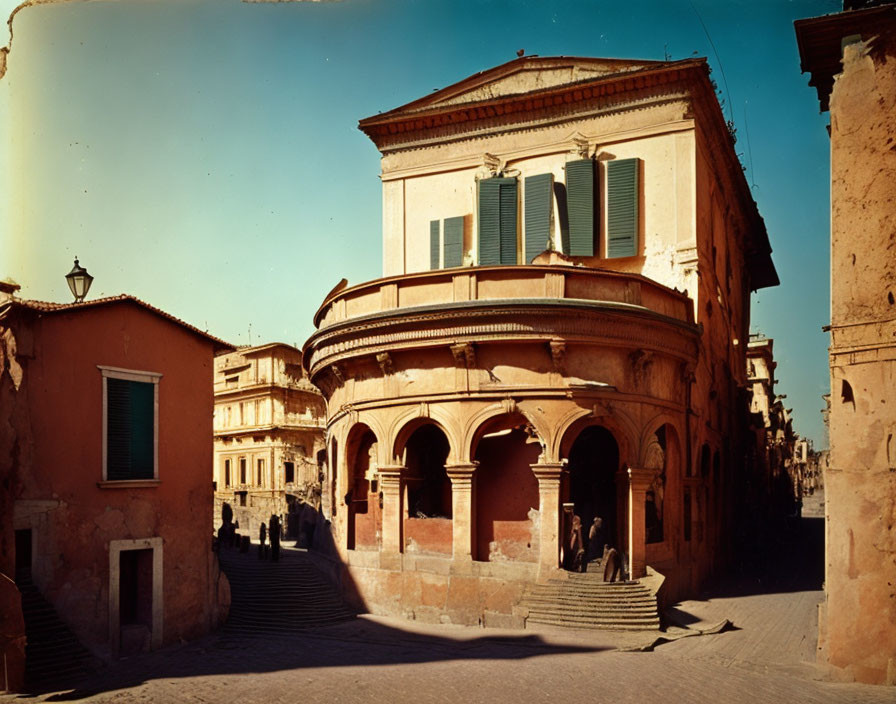 European cobblestone street scene with curved corner building and shuttered windows.