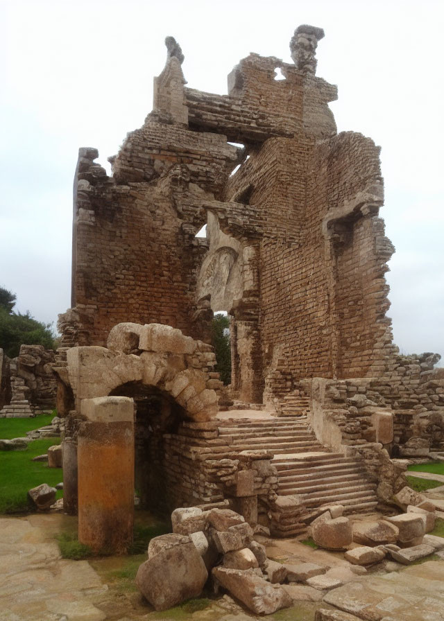 Ancient stone ruins with arches and stairway in overgrown setting