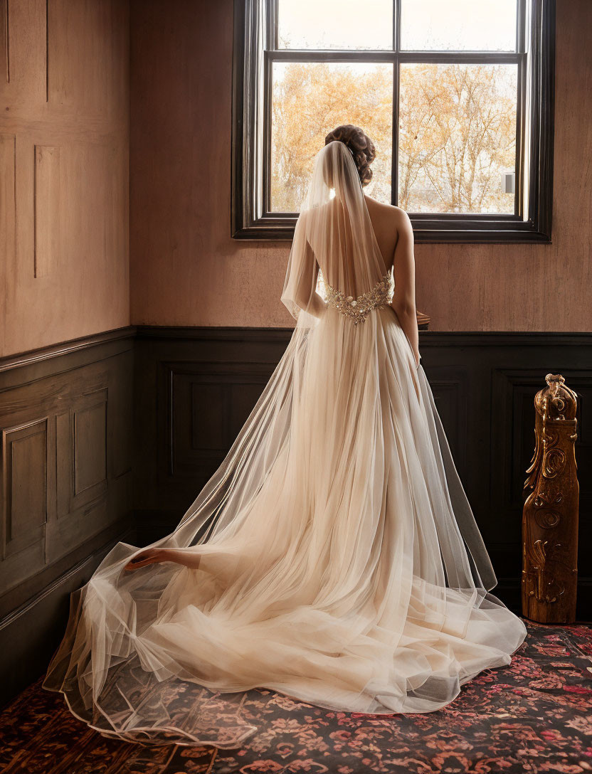 Bride in elegant wedding dress by window with flowing veil