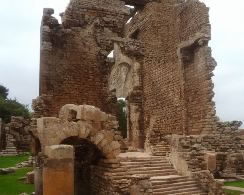 Ancient stone ruins with arches and stairway in overgrown setting