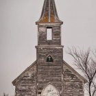 Desolate landscape at dusk with old wooden church and figures around fires