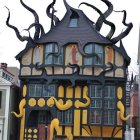 Whimsical yellow house painting with twisted black branches and vibrant flowers