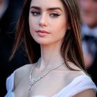 Young woman with long brown hair in ruffled top and gold necklace