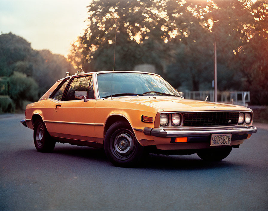 Classic Orange Car Parked on Road at Sunset with Trees