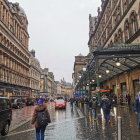 Vintage cars and umbrellas in rainy city street scene with warm amber tones