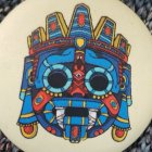 Vibrant Aztec sun stone sculpture with intricate designs in blue, red, and yellow.