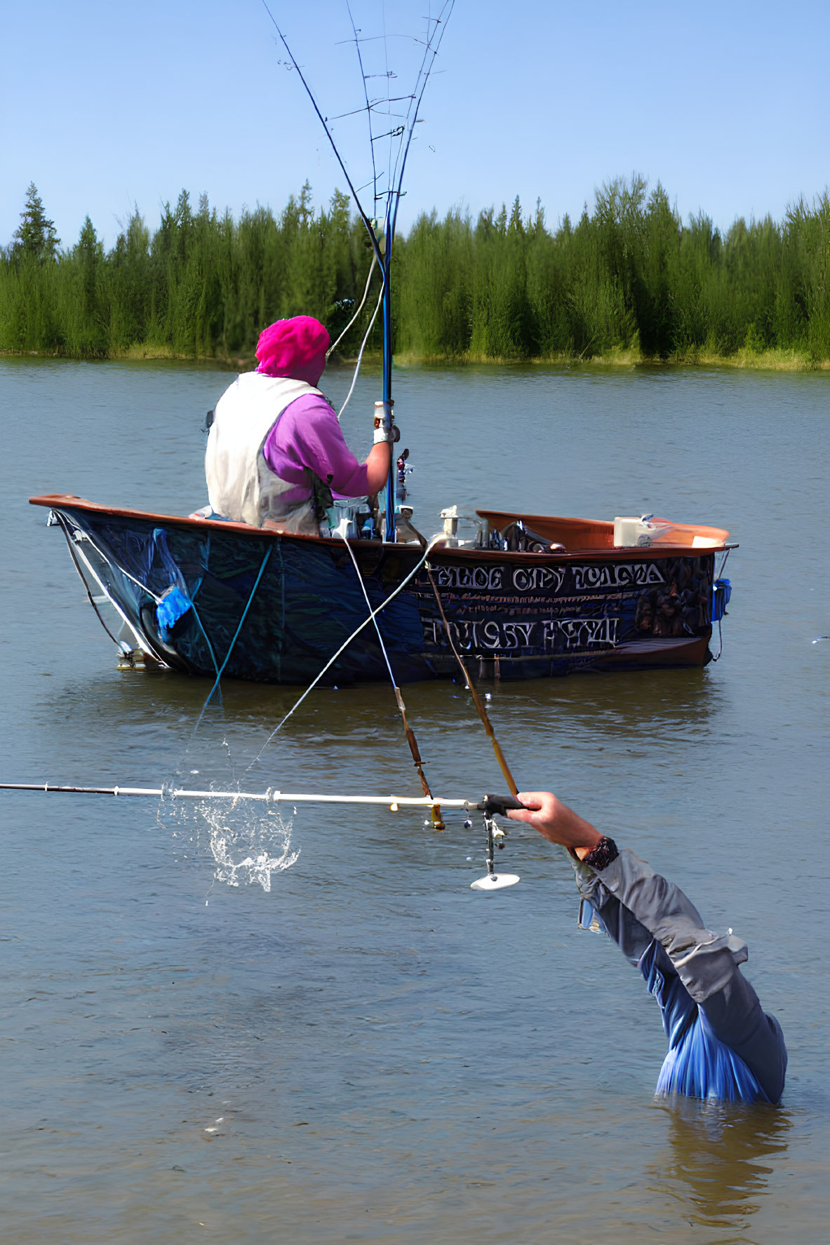 Person fishing from blue boat on calm lake with purple hat.