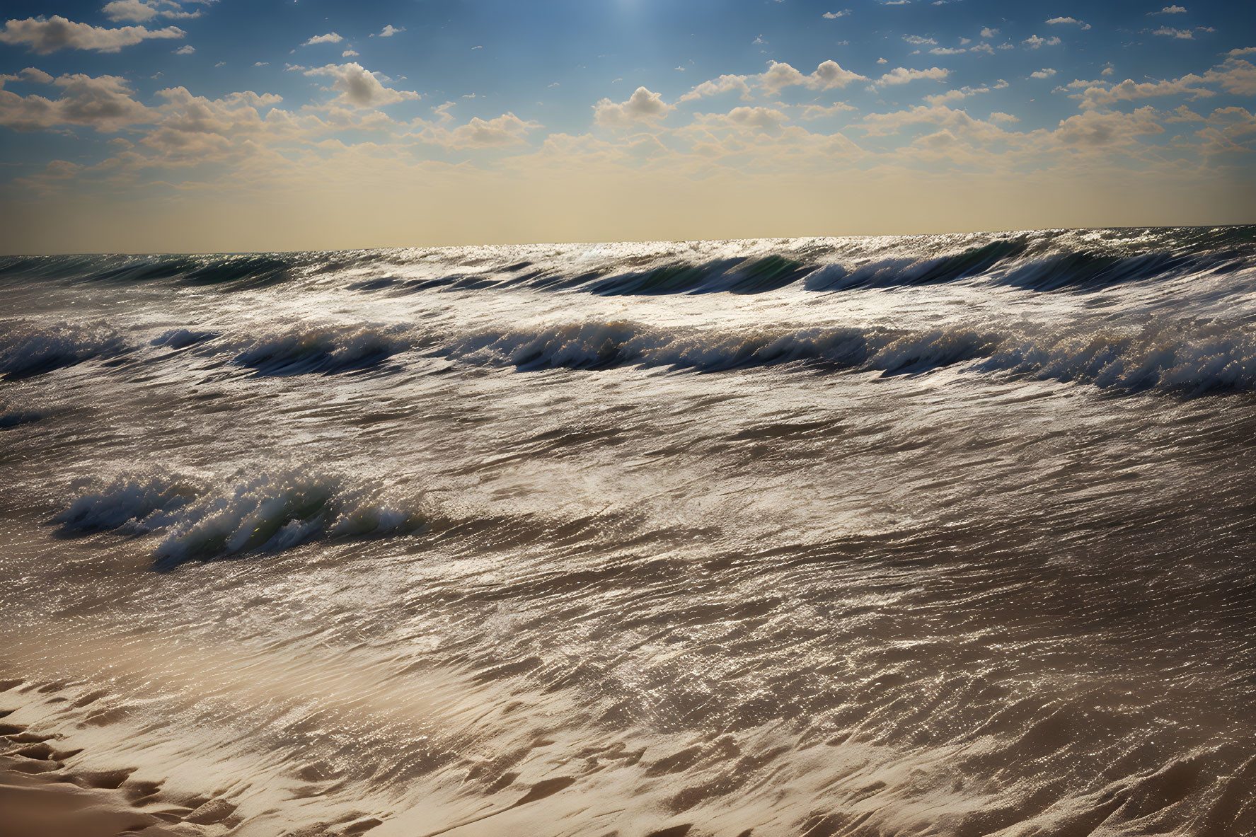 Ocean waves crashing on sandy beach under cloudy sky with sunlight breaking through