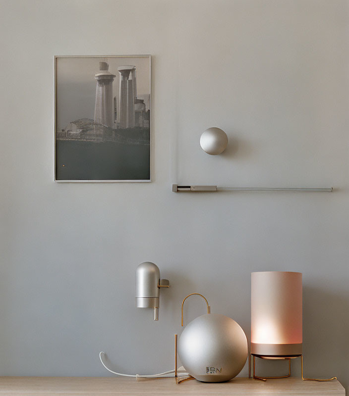 Minimalist interior with framed cityscape photo, wall lamp, shelf, and decorative objects.