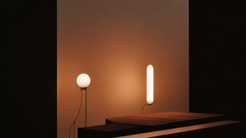 Modern lamps with spherical and oblong glowing bulbs on dark surface