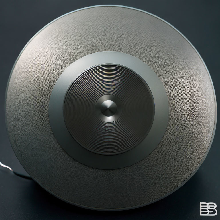 Circular Grey Speaker with Textured Fabric Cover and Metallic Control Knob