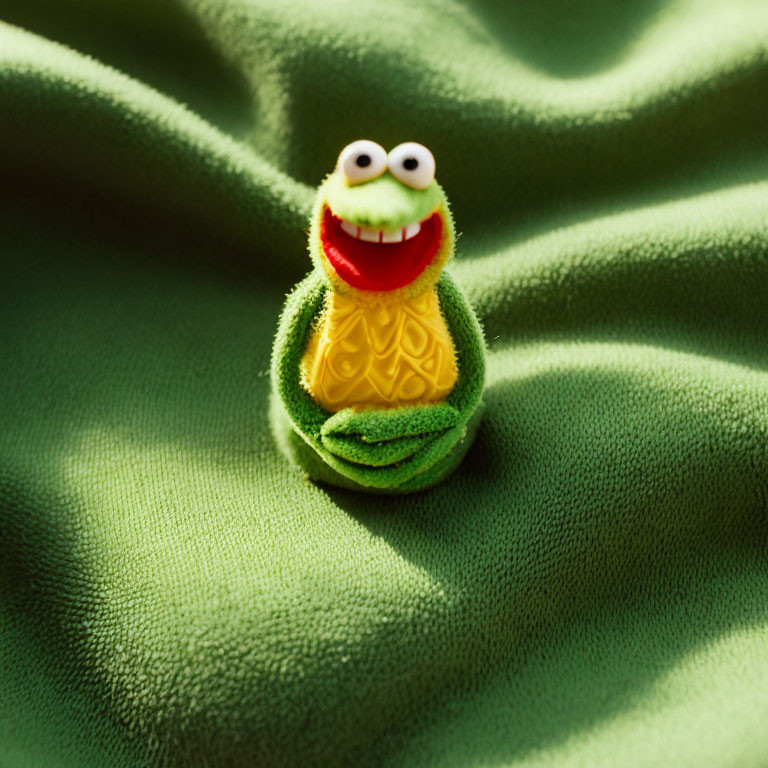 Kermit the Frog Toy on Green Textured Fabric Mimicking Lily Pad Environment