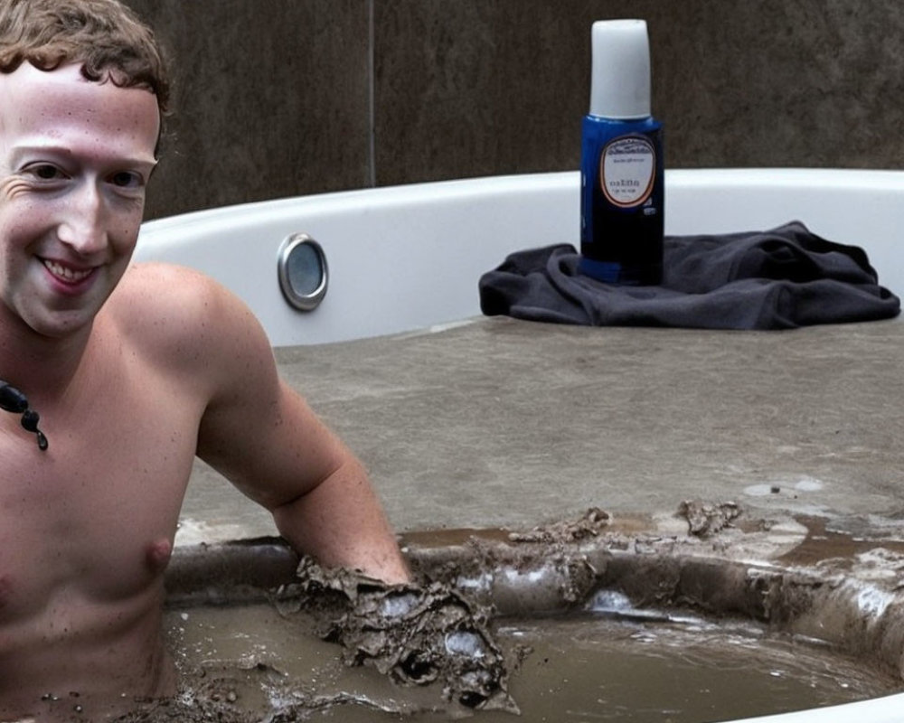 Smiling person in mud-filled bathtub with bottle and towel