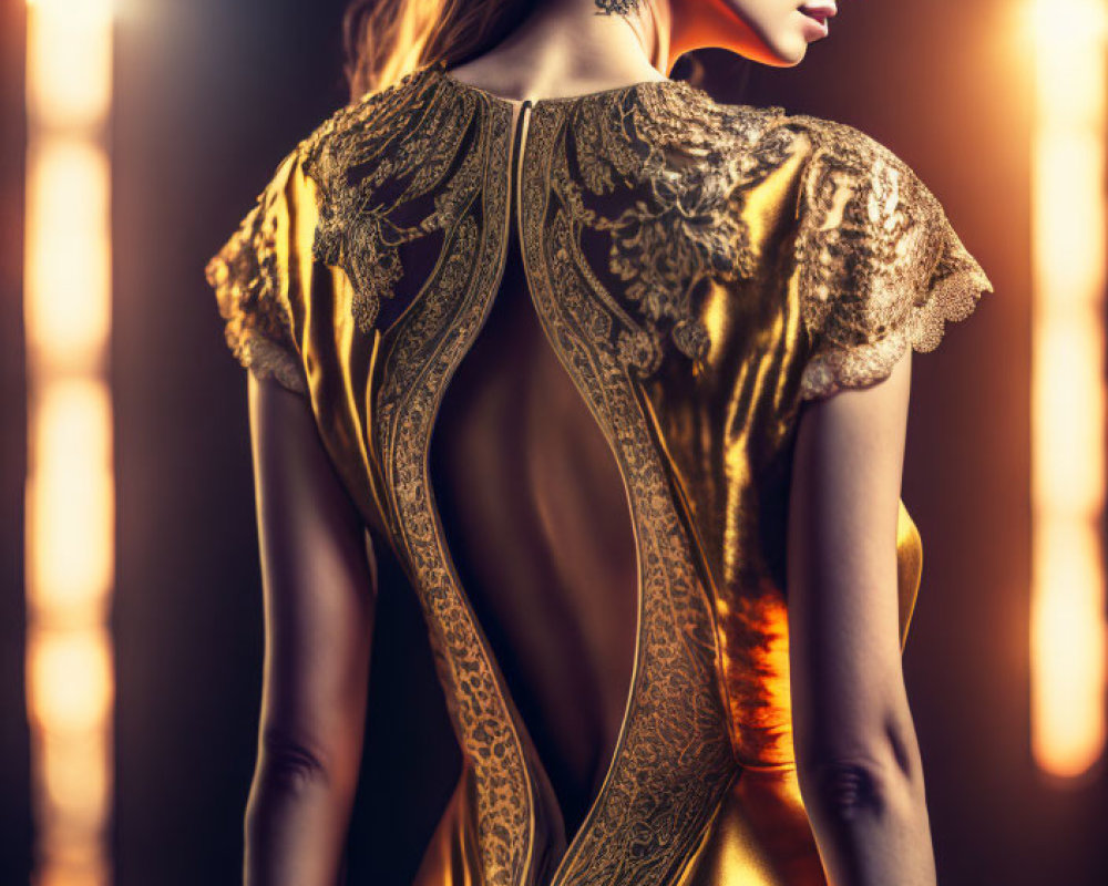 Woman models elegant gold dress with lace back design in dramatic lighting