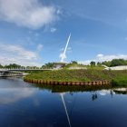 Tranquil lakeside village with rocket launch and lush greenery