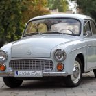 Vintage light blue car with gold trim in historical courtyard.