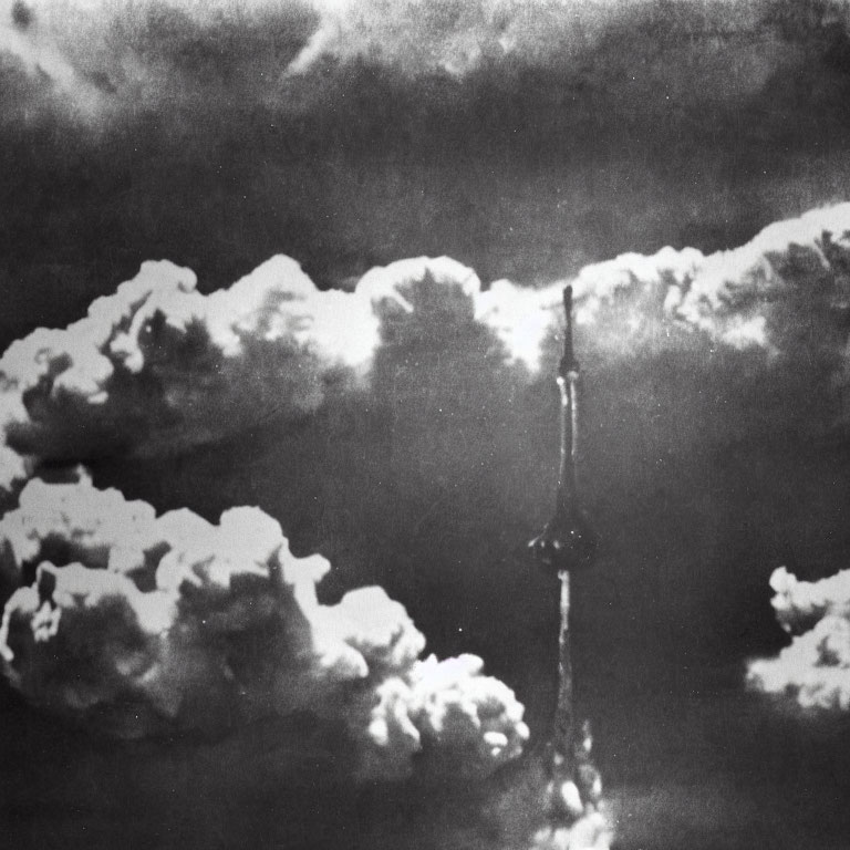 Monochrome image of towering nuclear explosion cloud among scattered sky clouds