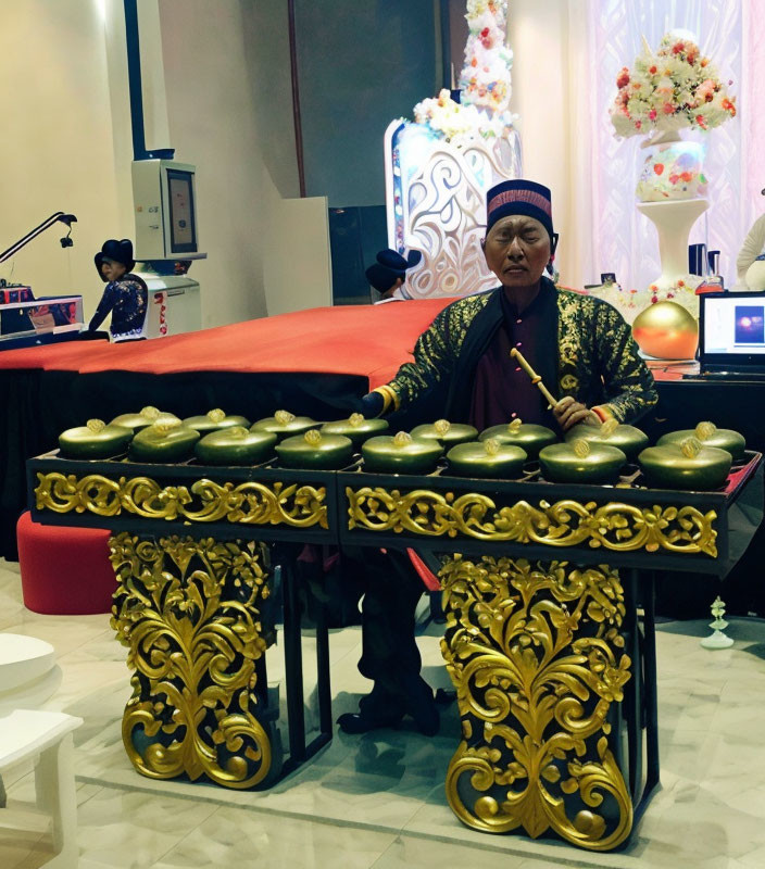 Traditional attire person playing gamelan at event with floral background