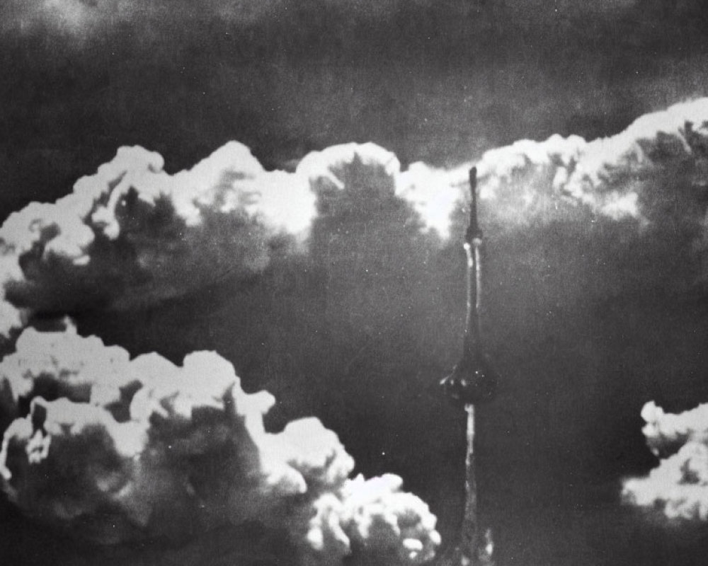 Monochrome image of towering nuclear explosion cloud among scattered sky clouds