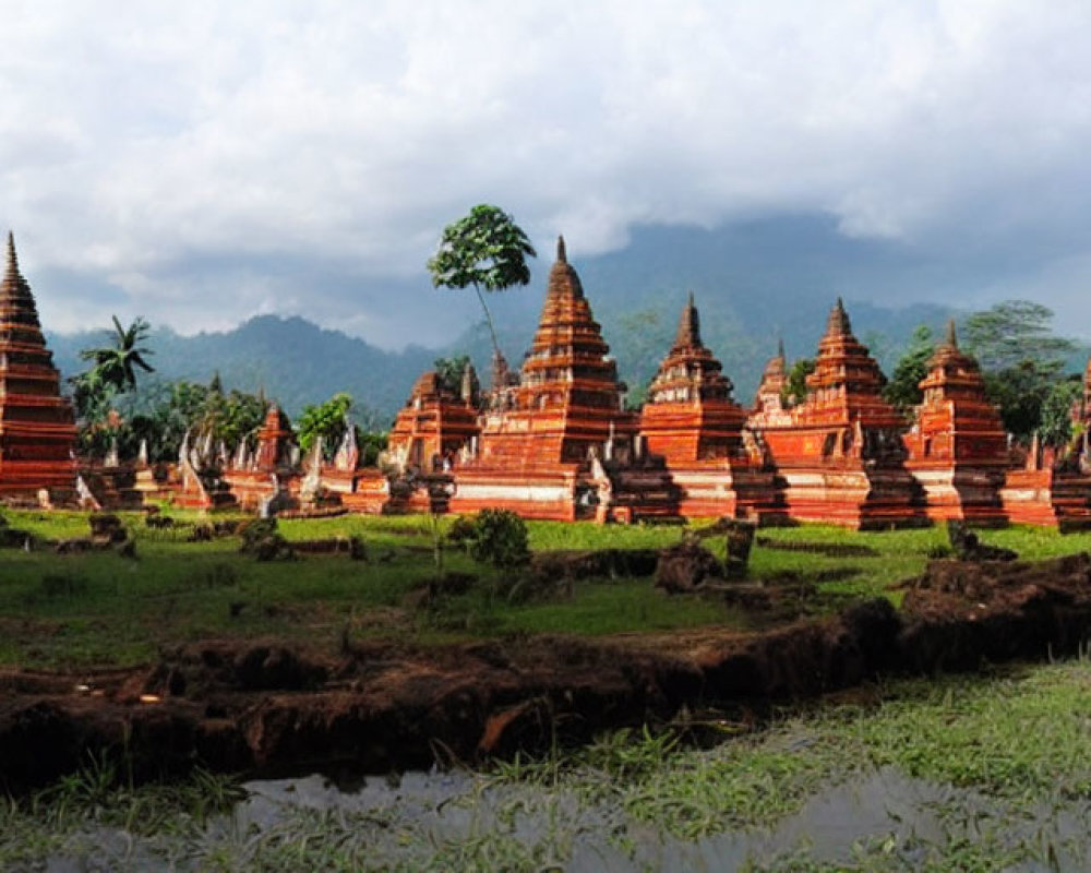 Ancient reddish-brown stupas in lush greenery with misty mountain backdrop.