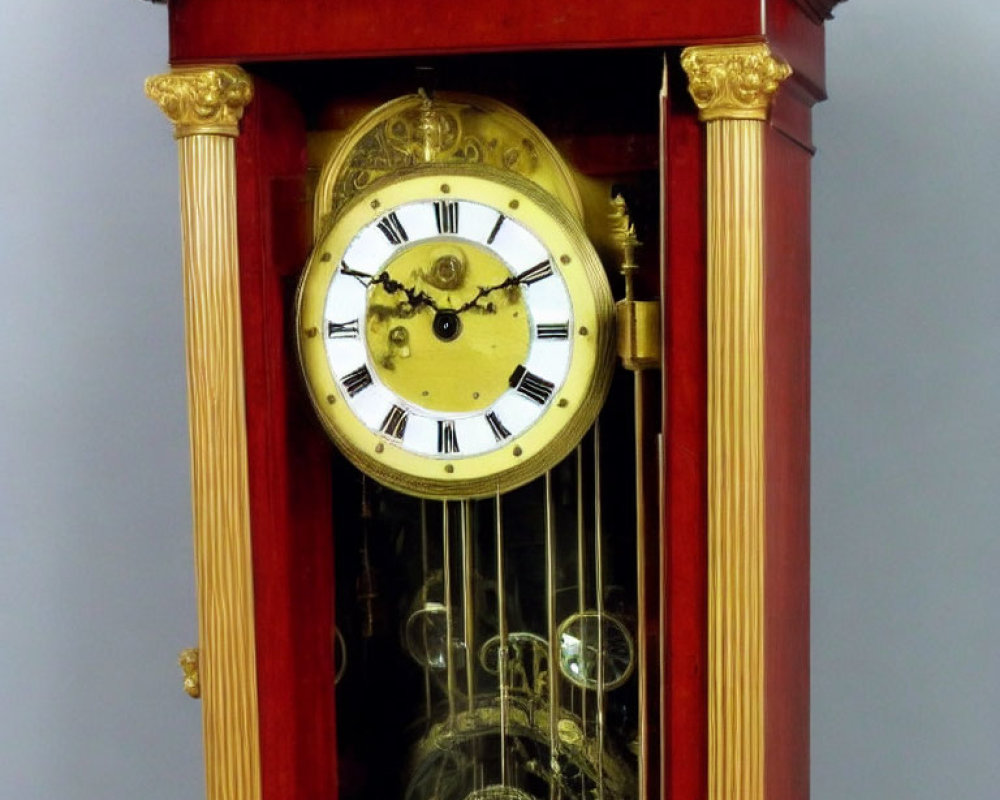 Vintage Grandfather Clock with Gold-Faced Dial and Visible Pendulum in Red Wooden Cabinet