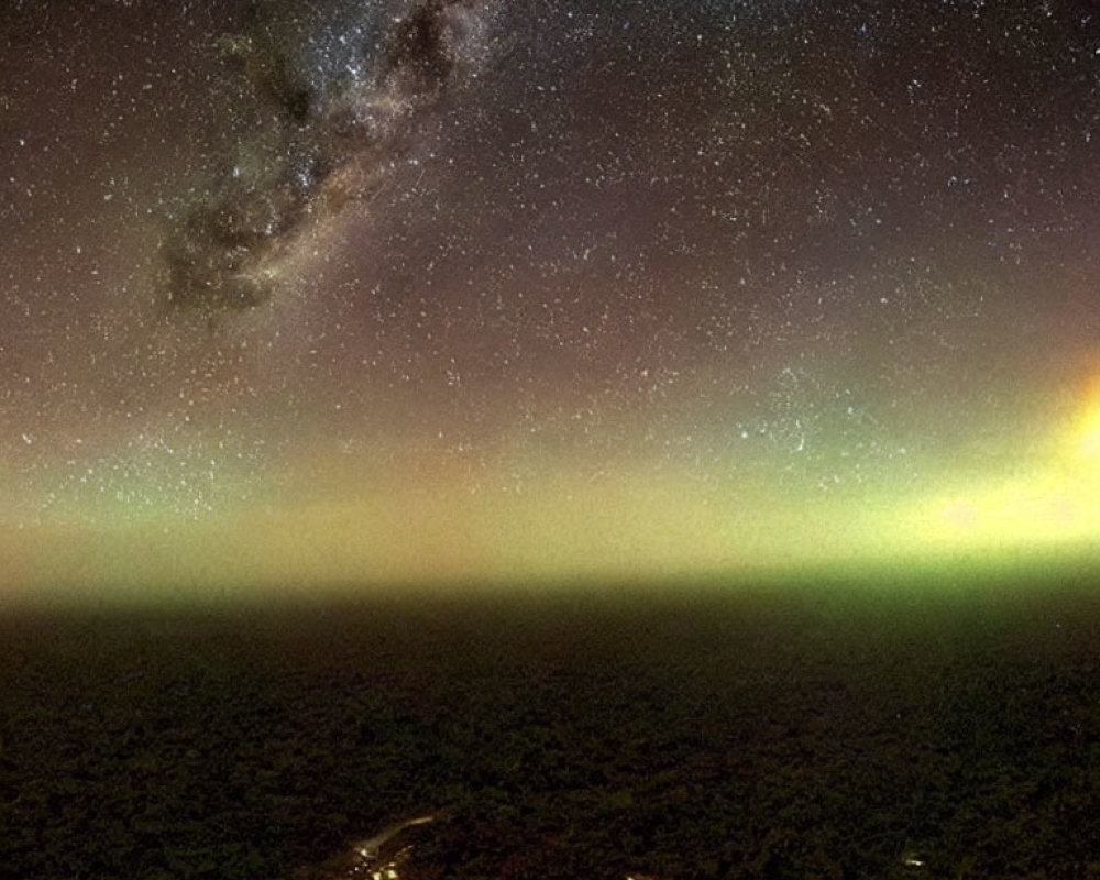 Starry Night Sky with Milky Way and Aurora above Dimly Lit Landscape