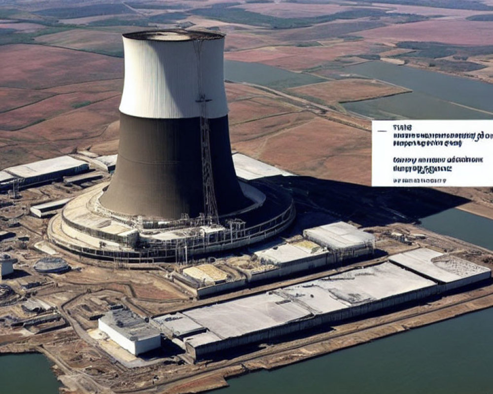 Large nuclear power plant with cooling tower in agricultural landscape