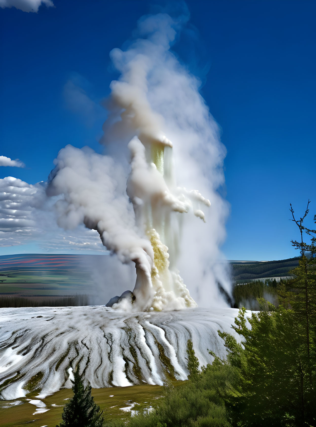 Powerful geyser eruption against blue sky and hills