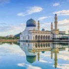 Majestic mosque with blue domes and spires reflected in water