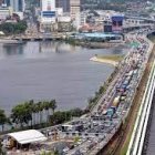 Cityscape with River, Roads, Buildings, and Vehicles in Cloudy Aerial View