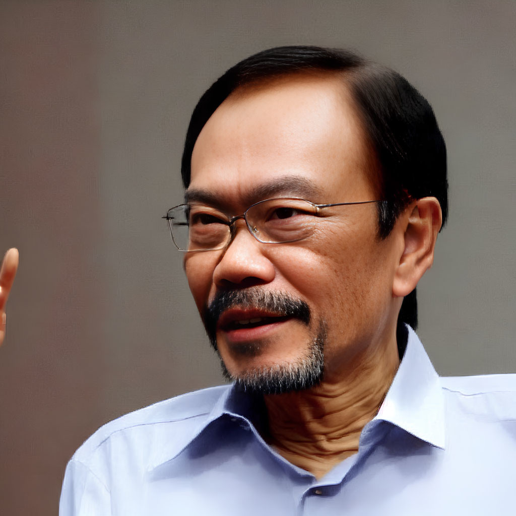 Middle-aged man with goatee and glasses in blue shirt smiling slightly