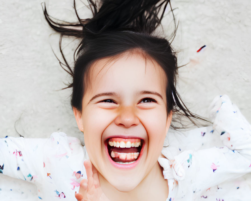 Young girl laughing with hair blowing in floral shirt