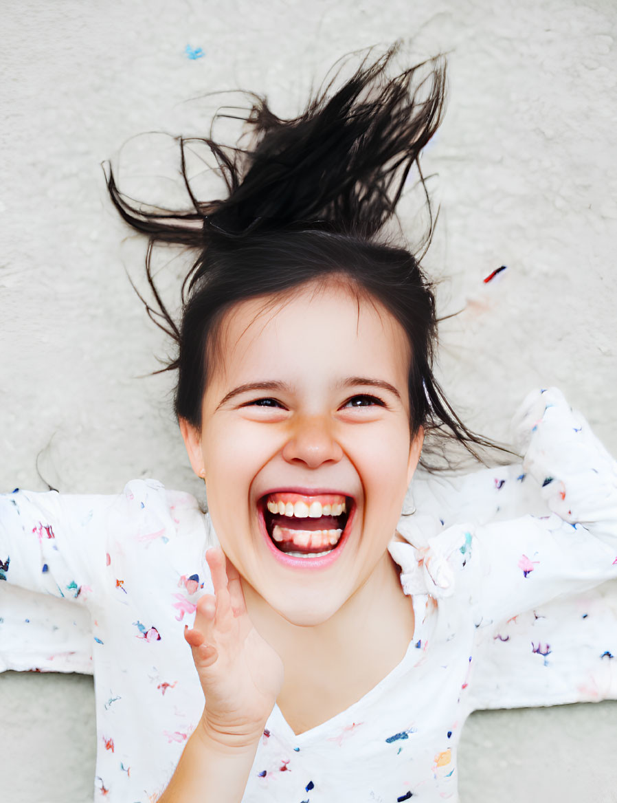 Young girl laughing with hair blowing in floral shirt