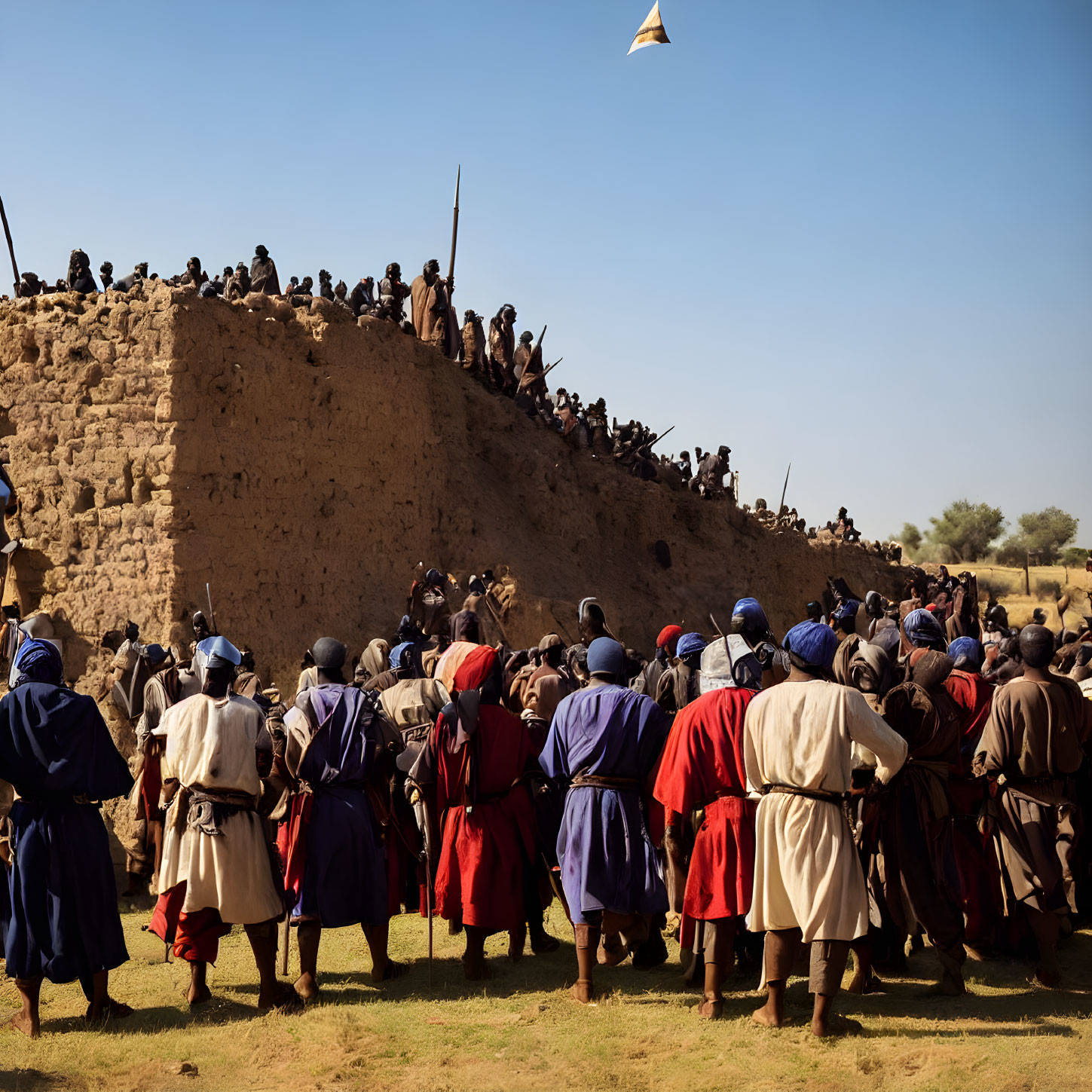 Historical reenactment with individuals in period clothing around earthen structure