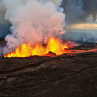 Volcanic landscape with erupting lava, flowing streams, and smoking volcano