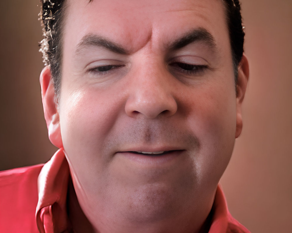 Person in red shirt smirking against blurred background